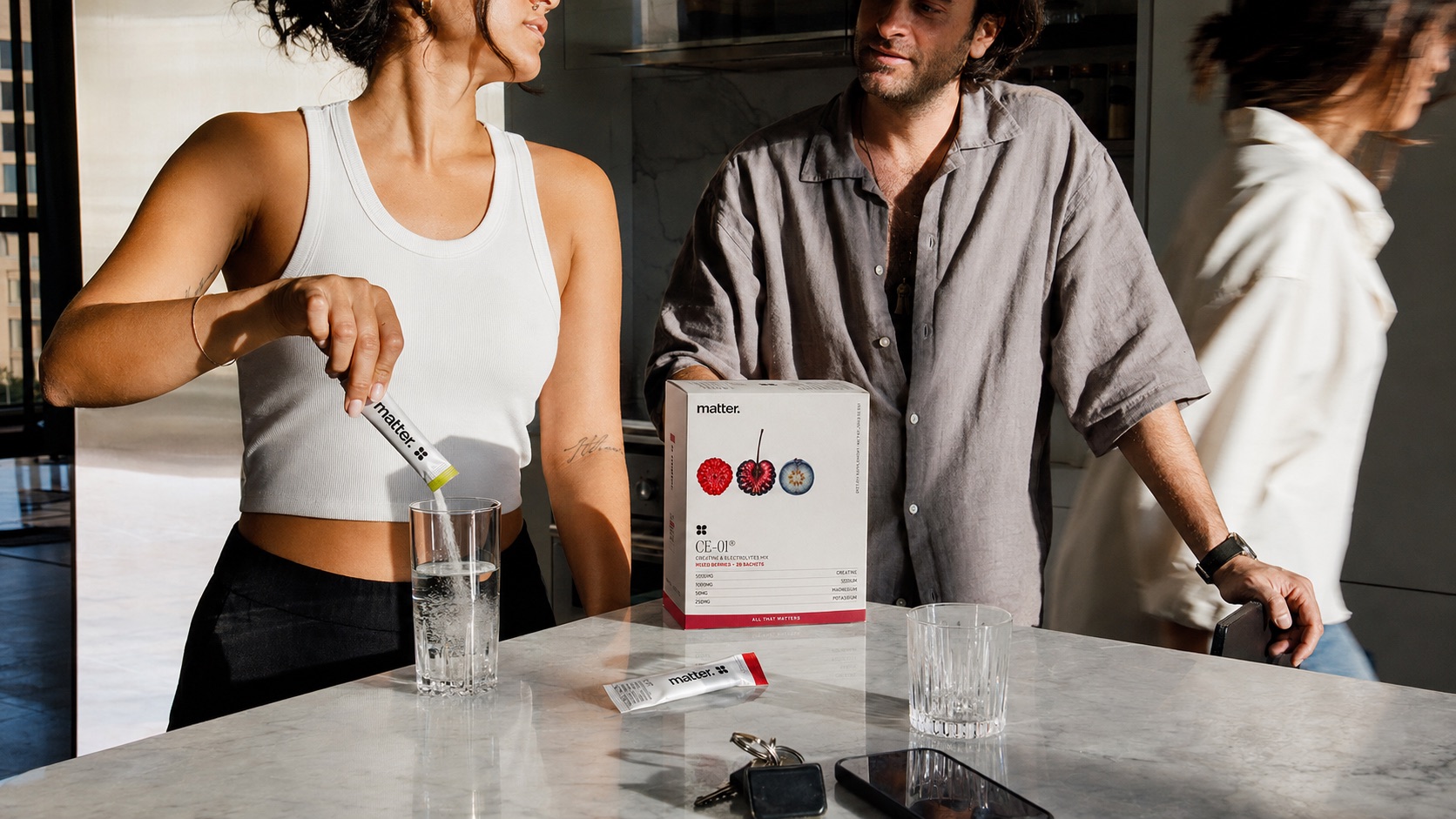 Two people at a kitchen counter with a CE-01 box and a glass of water