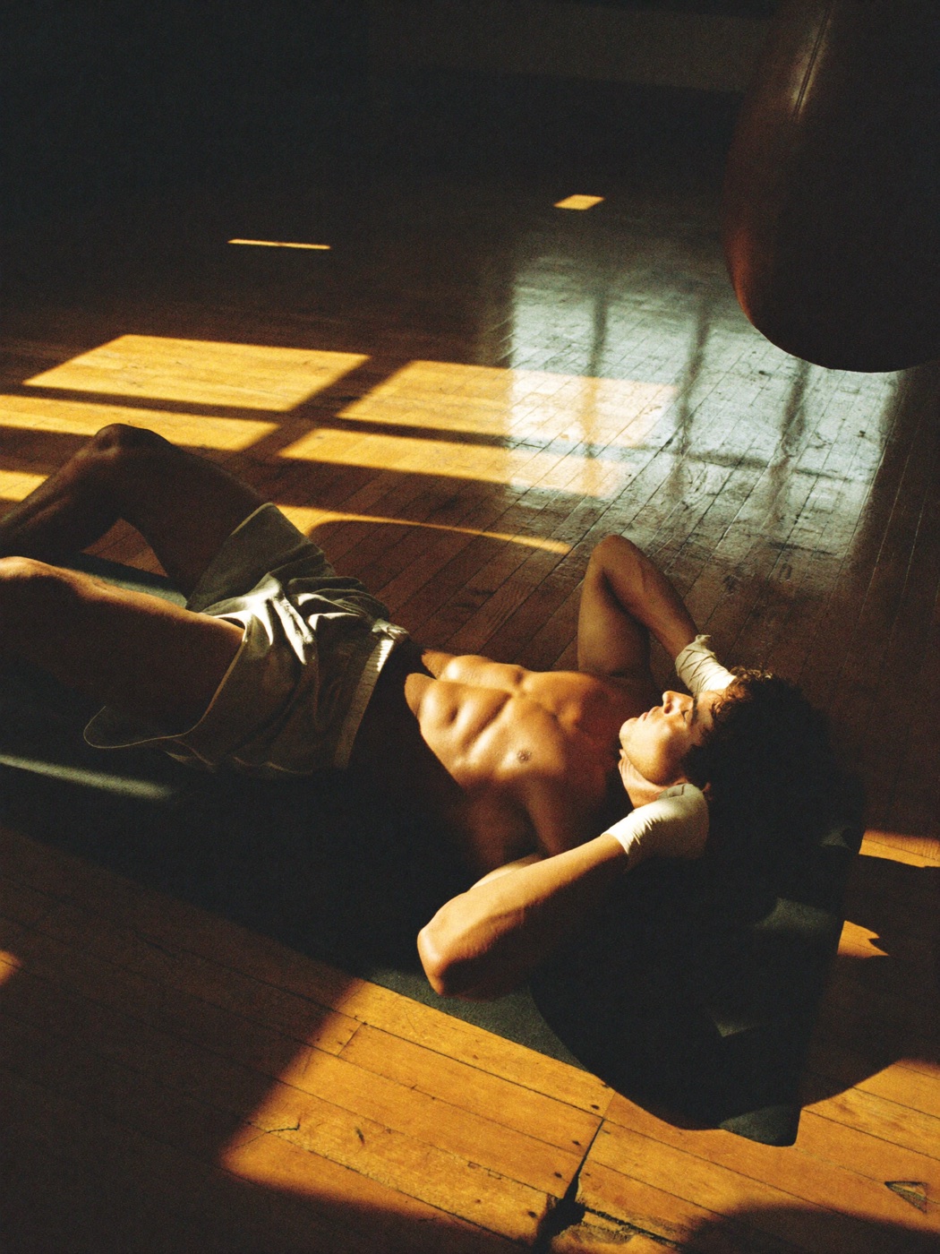 A man resting on a sunlit gym floor